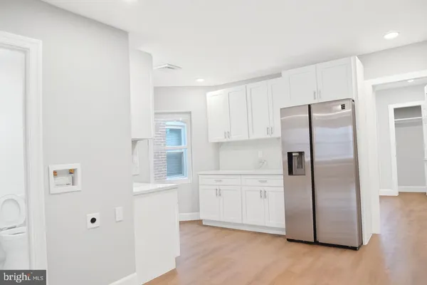 a kitchen with stainless steel appliances a refrigerator a sink and white cabinets