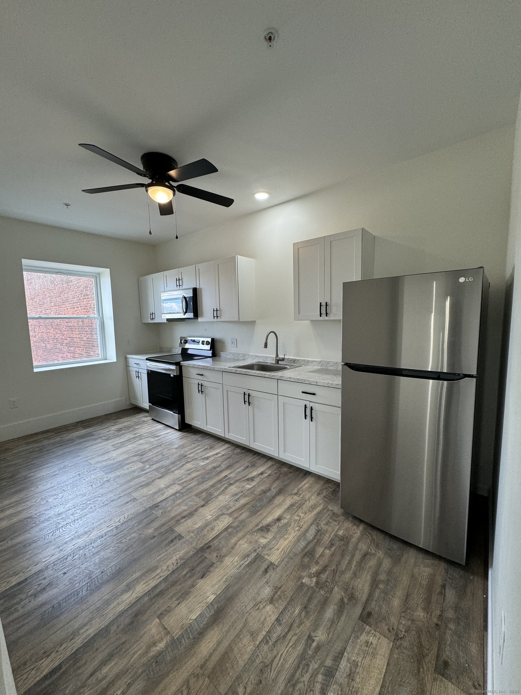 a kitchen with stainless steel appliances granite countertop a refrigerator a sink dishwasher a stove with wooden floor and cabinets