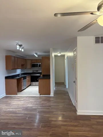 a large kitchen with stainless steel appliances kitchen island a large counter top and a wooden floor