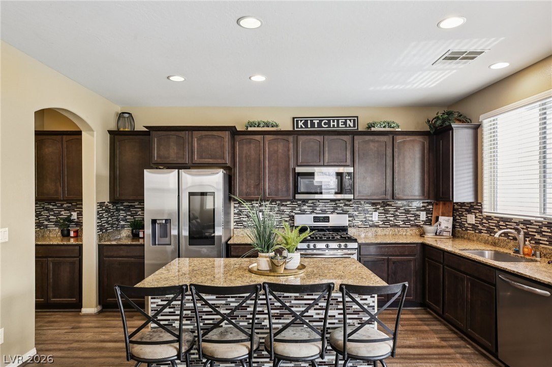 3957 East Carla Ann Road North Las Vegas, NV 89081 - Photo 3 of 35 Kitchen with dark wood finish cabinets, stainless steel appliances, light stone counters, dark wood-style flooring, and recessed lighting