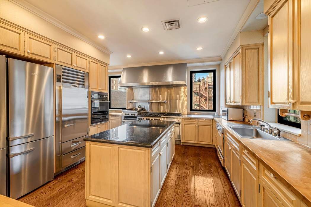 740 Park Avenue, Unit 6/7D Manhattan, NY 10021 - Photo 7 of 19 a kitchen with a refrigerator a sink and white cabinets