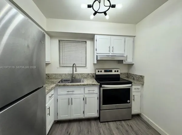 a kitchen with stainless steel appliances granite countertop a stove and white cabinets