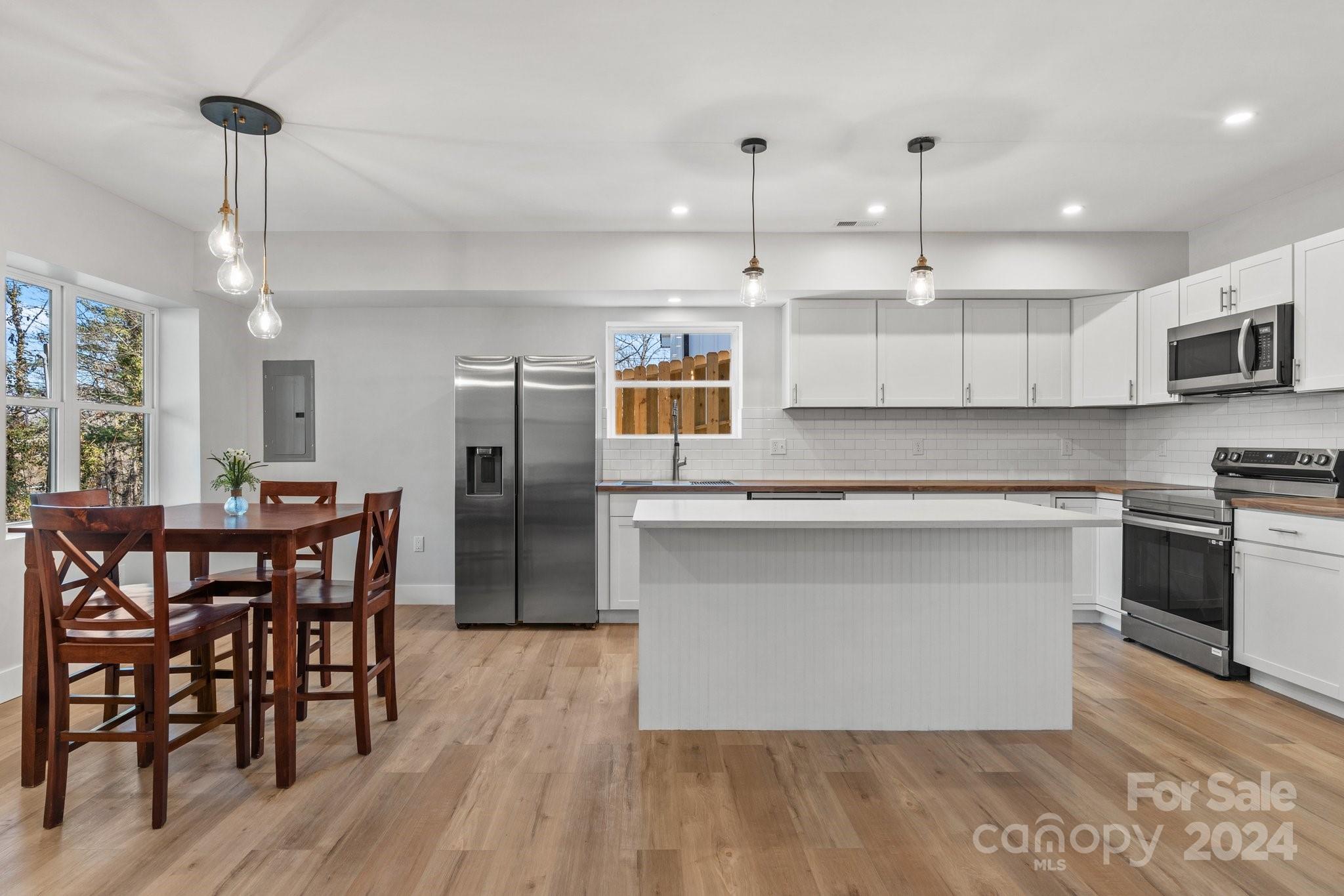 32 Access Road Black Mountain, NC 28711 - Photo 6 of 34 a kitchen with stainless steel appliances granite countertop a stove a refrigerator a kitchen island a dining table and chairs with wooden floor