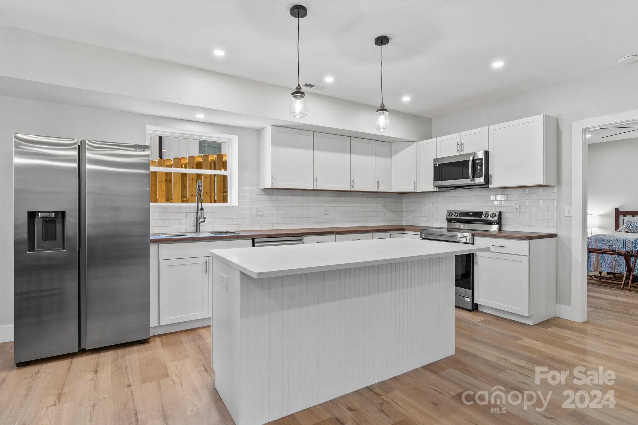 32 Access Road Black Mountain, NC 28711 - Photo 9 of 34 a kitchen with stainless steel appliances granite countertop a sink a stove a refrigerator and island with wooden floor