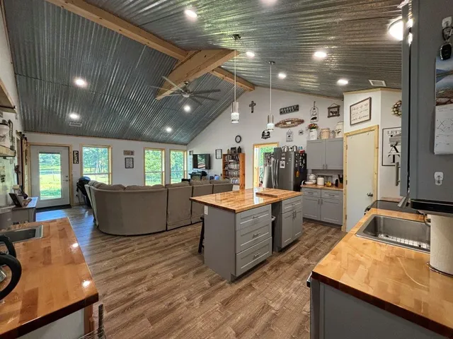 a kitchen with stainless steel appliances kitchen island granite countertop a table chairs and a refrigerator