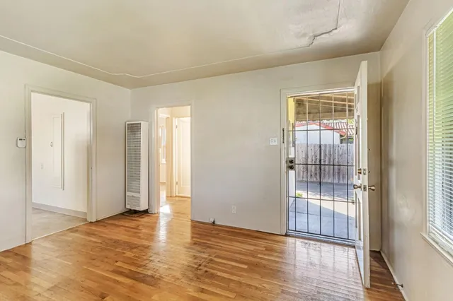 a view of empty room with wooden floor and fan