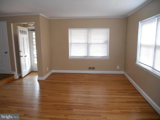 844 Bradhurst Road Baltimore, MD 21212 - Photo 5 of 17 an empty room with wooden floor and windows