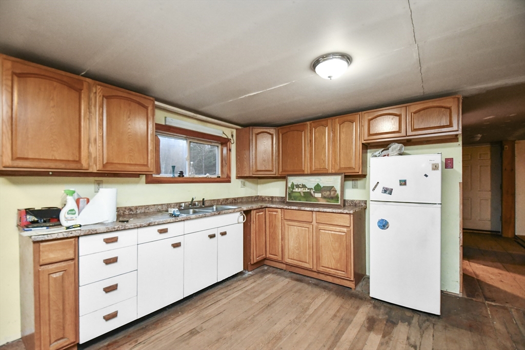 56 Pine Hill Road Orange, MA 01364 - Photo 13 of 30 a kitchen with stainless steel appliances granite countertop a refrigerator a sink dishwasher and white cabinets with wooden floor