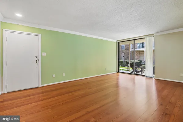 an empty room with wooden floor and a floor to ceiling window