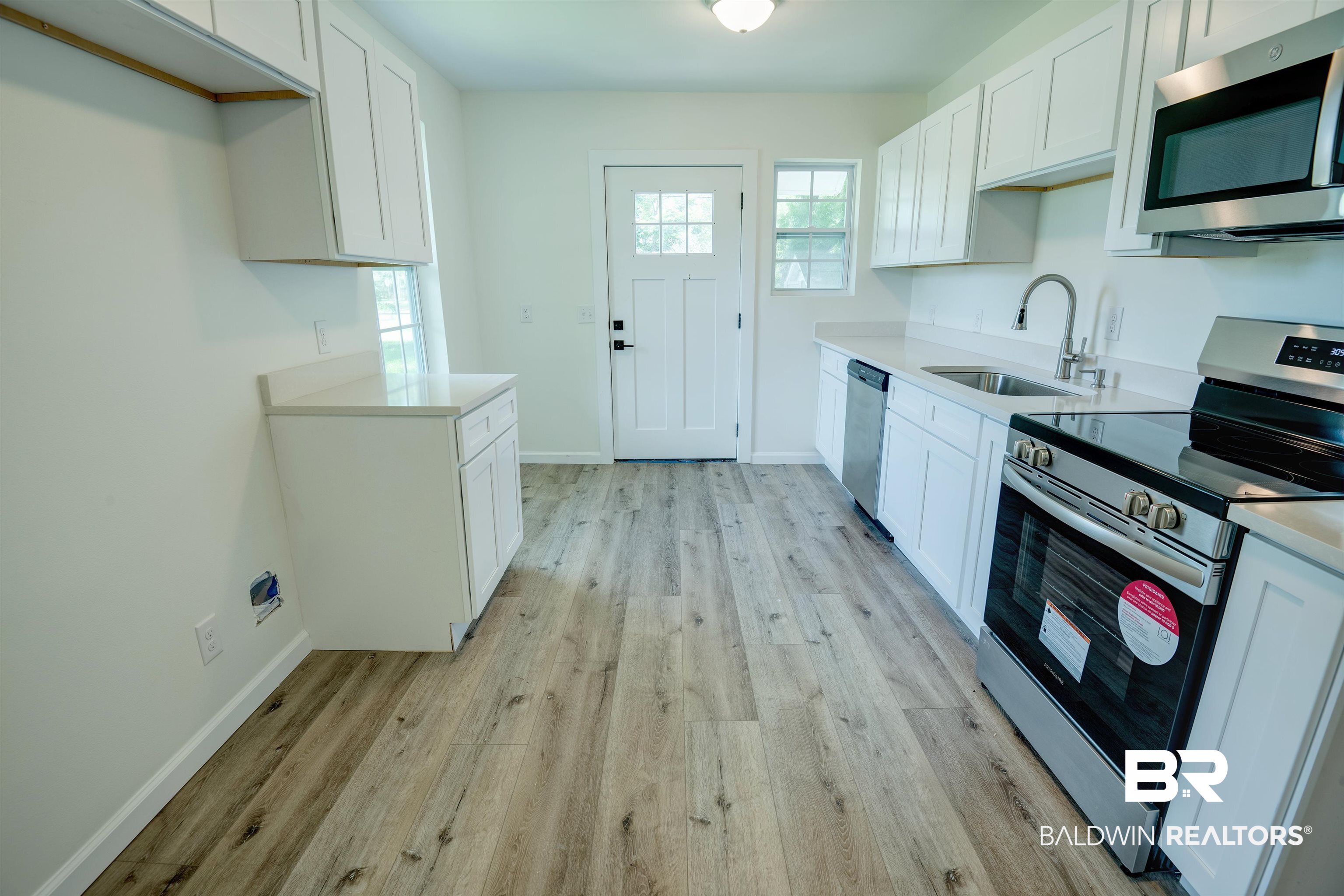 510 East Myrtle Avenue Foley, AL 36535 - Photo 7 of 22 Kitchen with appliances with stainless steel finishes, light wood-style flooring, light countertops, and white cabinetry
