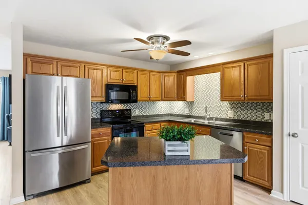 a kitchen with stainless steel appliances granite countertop a sink a stove and a refrigerator