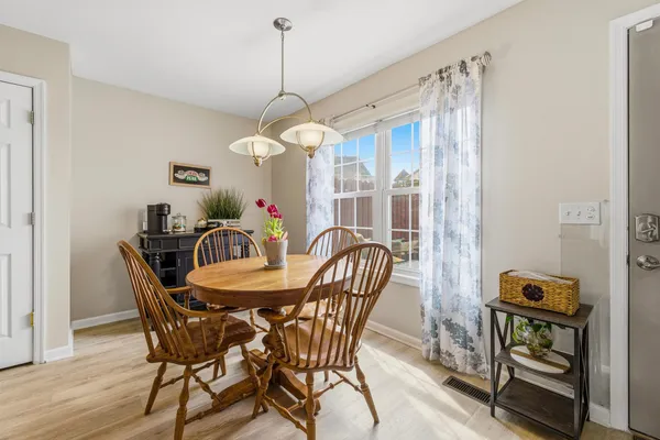 a dining room with wooden floor a chandelier a wooden table and chairs