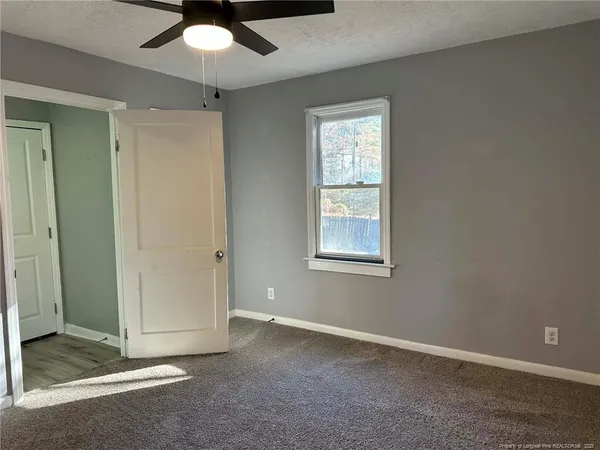 an empty room with a ceiling fan and a window