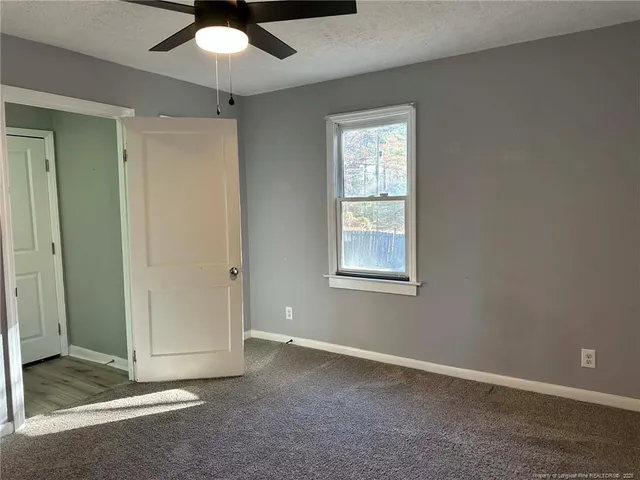 an empty room with a ceiling fan and a window