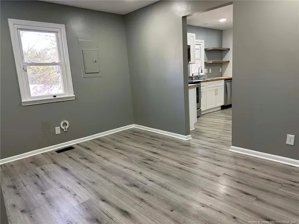 a view of empty room with wooden floor and window