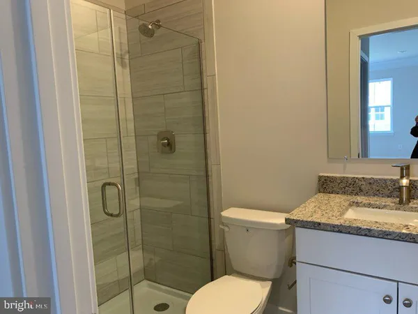 a bathroom with a granite countertop toilet a sink and shower