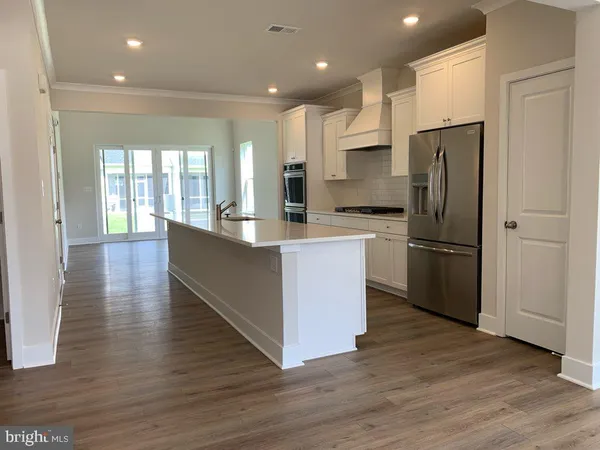 a kitchen with stainless steel appliances granite countertop a refrigerator a sink dishwasher a oven and a dining table with wooden floor