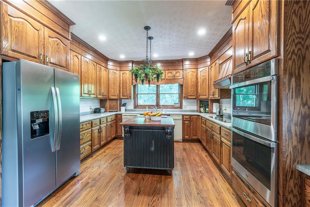 755 Harris Road Jasper, GA 30143 - Photo 19 of 54 a kitchen with stainless steel appliances granite countertop a refrigerator a sink dishwasher a stove and white countertops with wooden floor