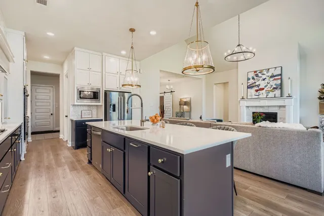 a kitchen with kitchen island stainless steel appliances a stove center island a refrigerator wooden floor and a fireplace