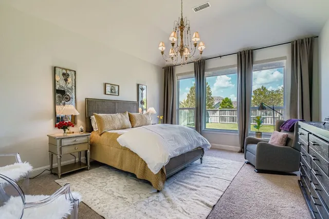 a spacious bedroom with a bed and a chandelier