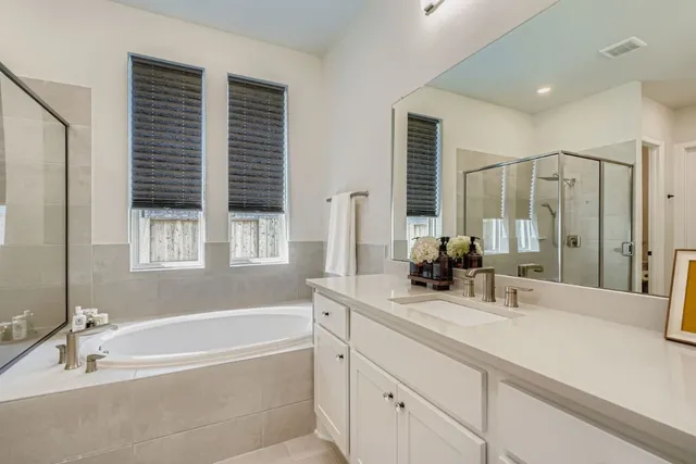 a bathroom with a tub a sink and a large mirror