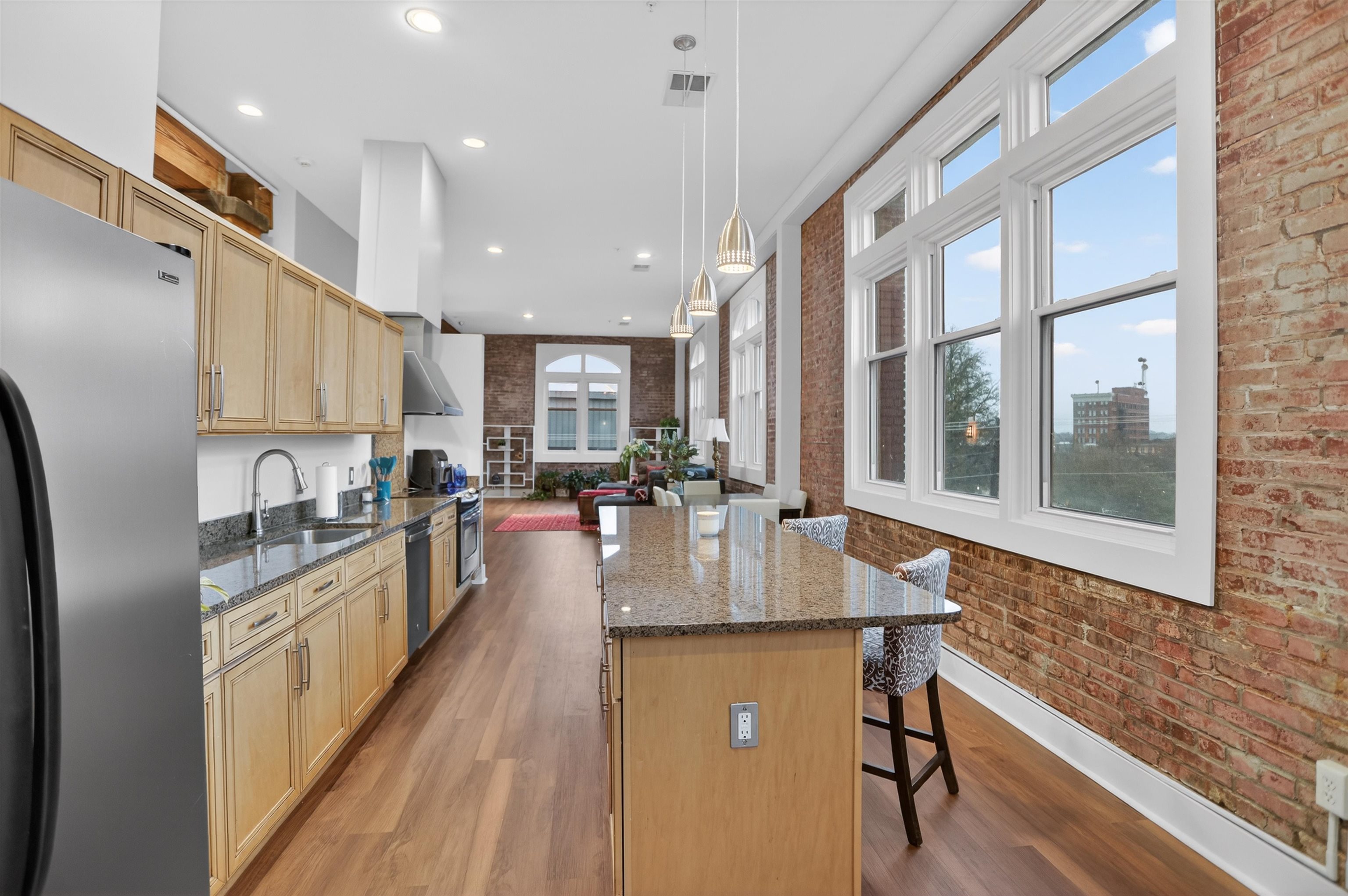 435 South Front Street, Unit 307 Memphis, TN 38103 - Photo 6 of 40 Kitchen with brick wall, dark stone counters, a breakfast bar, appliances with stainless steel finishes, and a kitchen island