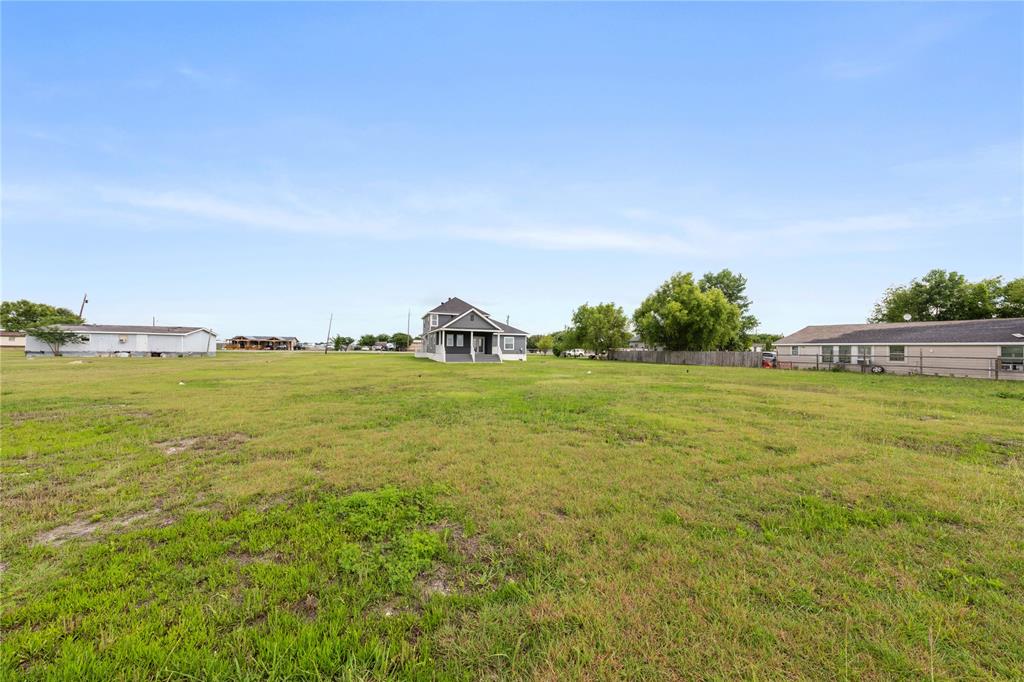 1128 Newton Road Ferris, TX 75125 - Photo 27 of 28 Expansive open lot featuring a central two-story residence with a gray exterior and white trim