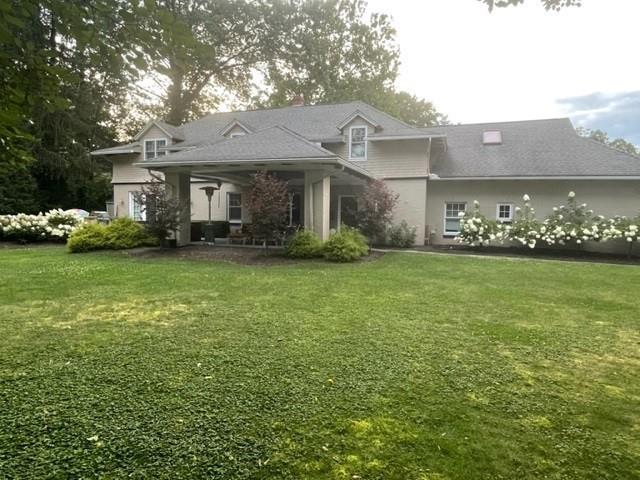 a view of a big house with a big yard and large trees