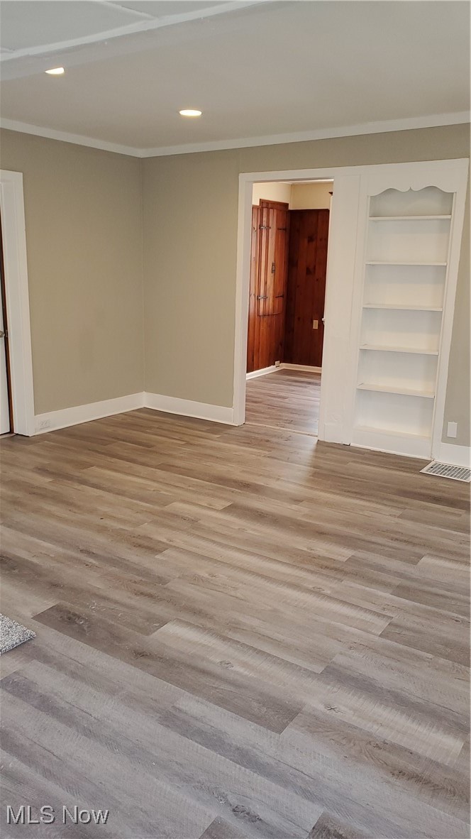 17610 Brazil Road Cleveland, OH 44119 - Photo 20 of 50 Empty room with crown molding, built in shelves, and light hardwood / wood-style flooring