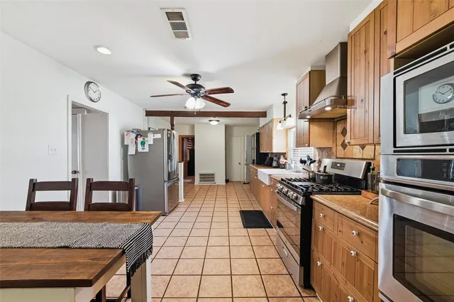 a kitchen with stainless steel appliances granite countertop a stove top oven a sink a counter space and cabinets