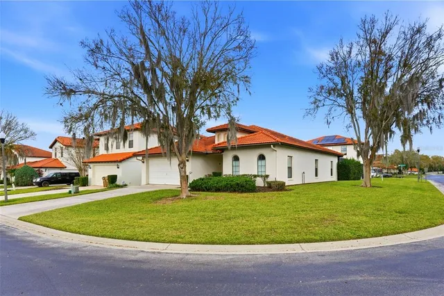 a view of white house with a big yard and palm trees