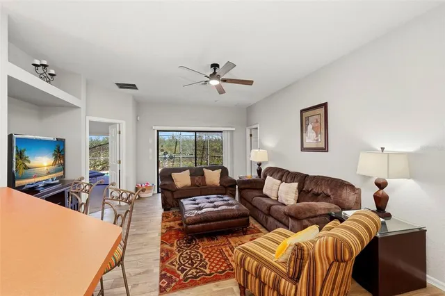 a living room with furniture a ceiling fan and a flat screen tv