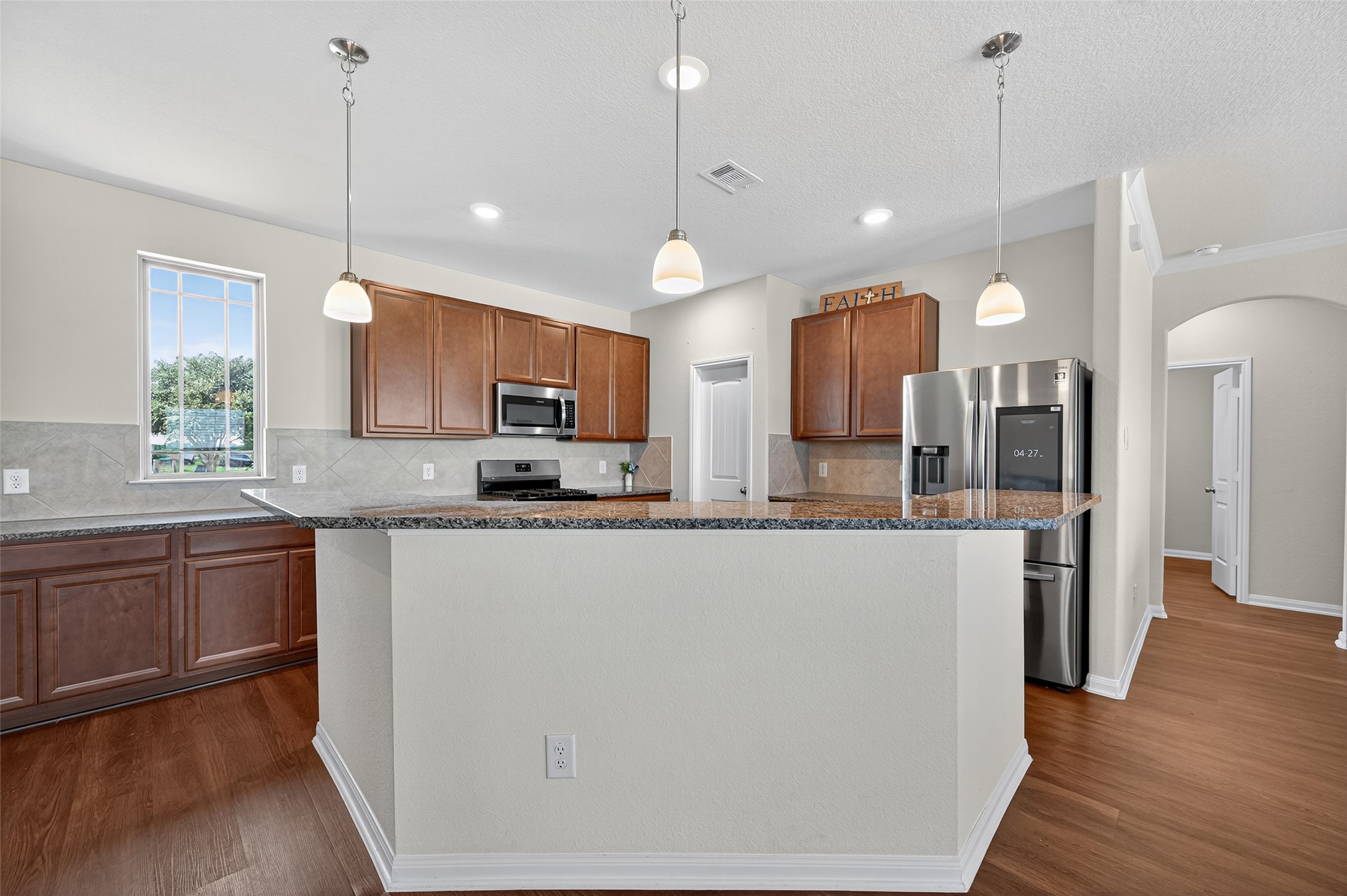 8007 Lehman Road Beasley, TX 77417 - Photo 10 of 47 a large kitchen with granite countertop a stove a sink a center island a refrigerator and a wooden floor