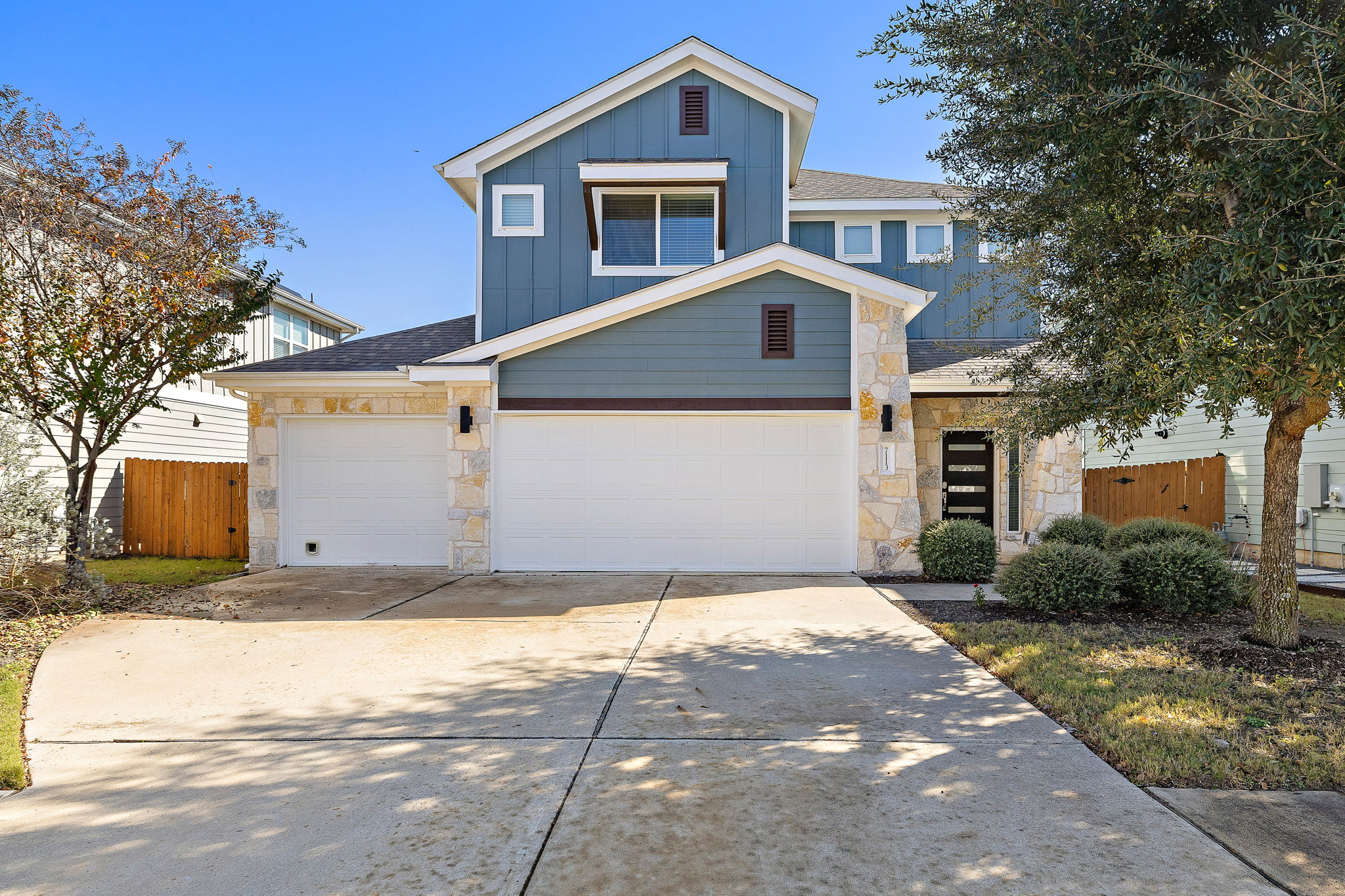 View of front of home with stone siding, board and batten siding, concrete driveway, a shingled roof, and a garage
