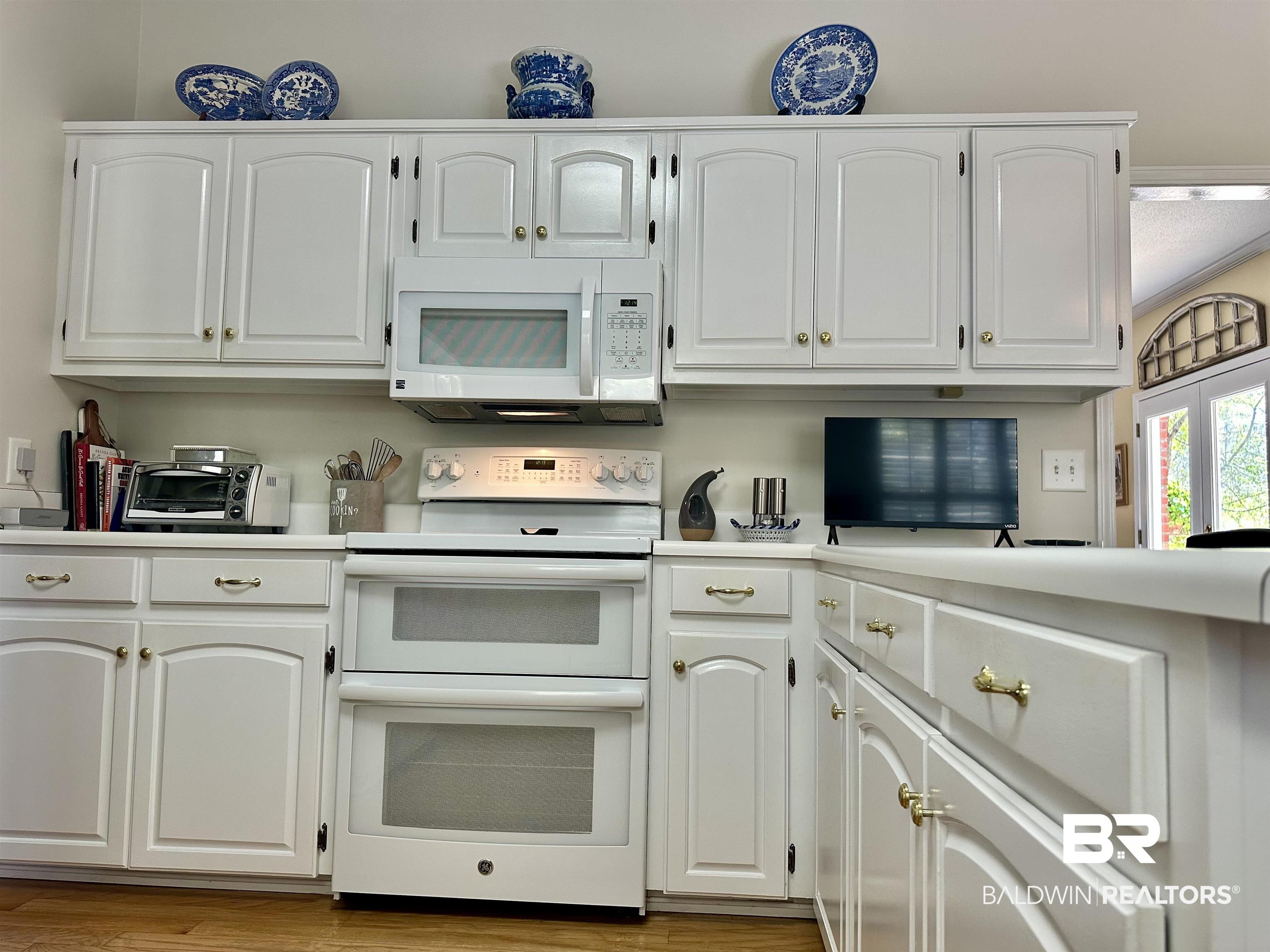 148 Brooks Boulevard Brewton, AL 36426 - Photo 13 of 45 Kitchen featuring light wood finished floors, a toaster, light countertops, white appliances, and white cabinetry