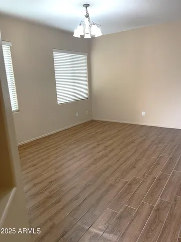 an empty room with wooden floor chandelier fan and windows