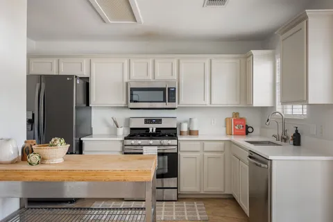 a kitchen with stainless steel appliances granite countertop white cabinets and a stove top oven