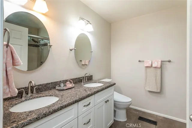 a bathroom with a granite countertop toilet a sink and a mirror