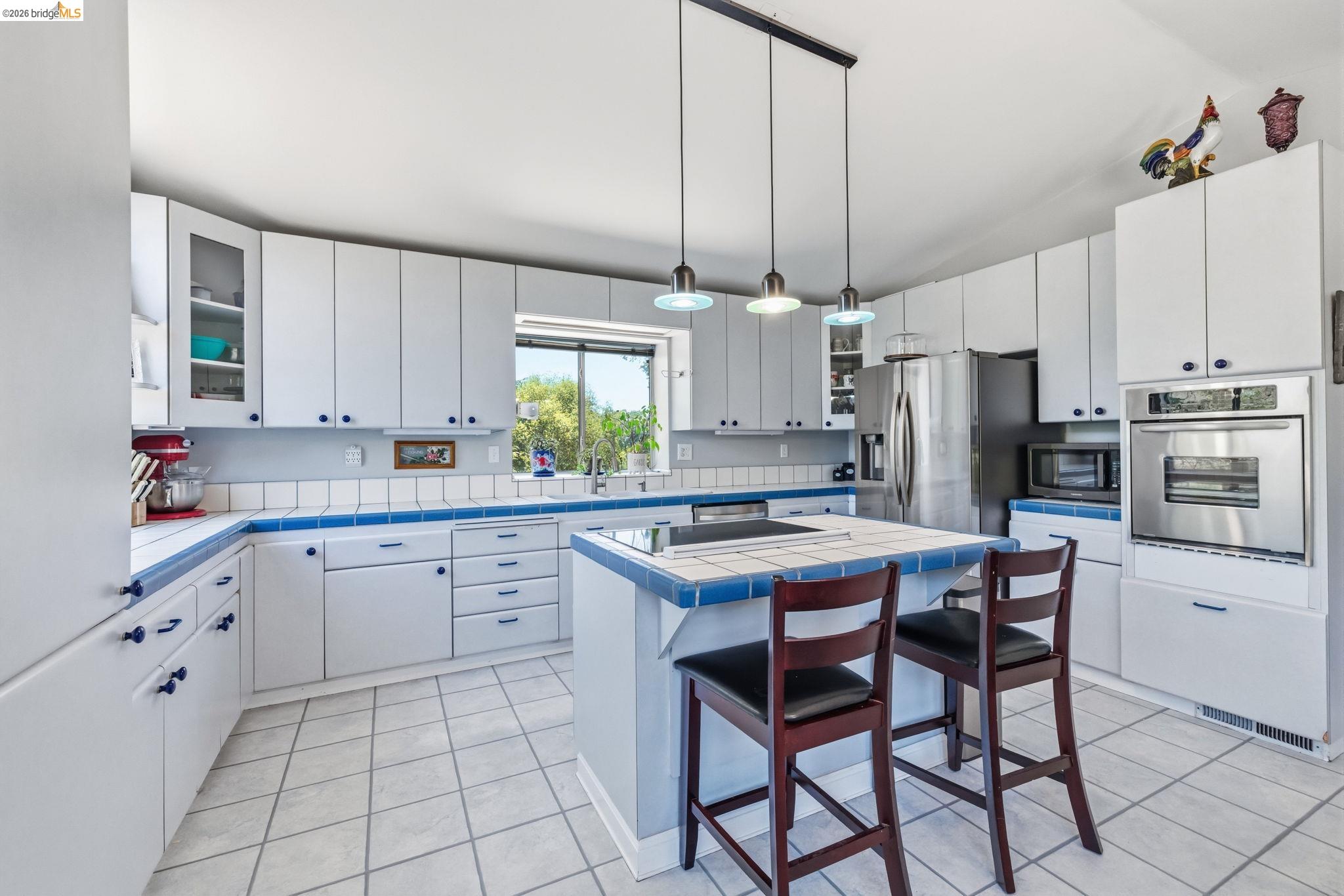 18570 Pradera Real Road Sonora, CA 95370 - Photo 44 of 66 Spacious kithen with abundant of cabinetry, stainless steel appliances, linoleum flooring, central island with cooktop, and multiple windows providing plenty of natural light.