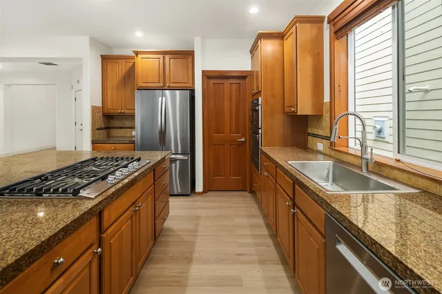 a kitchen with kitchen island granite countertop a sink stove and refrigerator