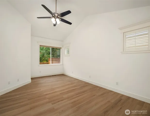 an empty room with wooden floor chandelier fan and windows