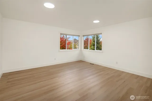 an empty room with wooden floor and window