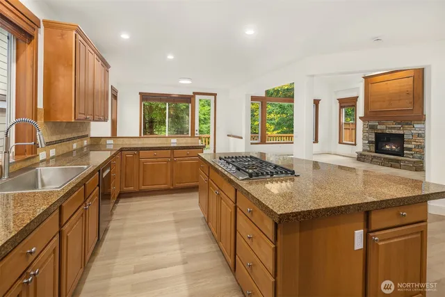 a kitchen with stainless steel appliances granite countertop a stove a sink dishwasher and a refrigerator with wooden cabinets