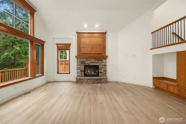 a view of an empty room with wooden floor fireplace and a window