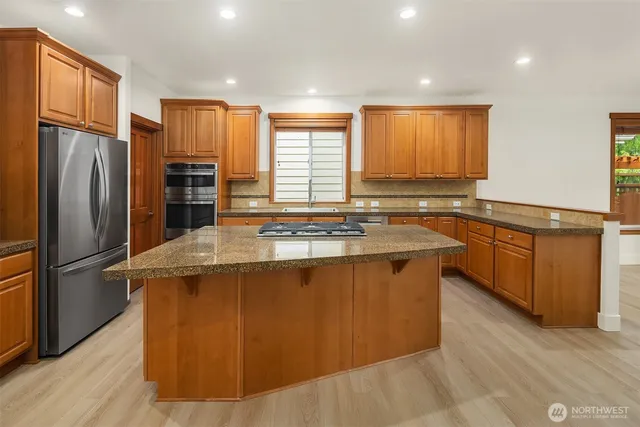 a kitchen with stainless steel appliances granite countertop a refrigerator a sink a stove and wooden floors