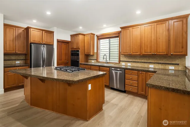 a kitchen with stainless steel appliances granite countertop a stove a sink dishwasher a refrigerator and cabinets with wooden floor