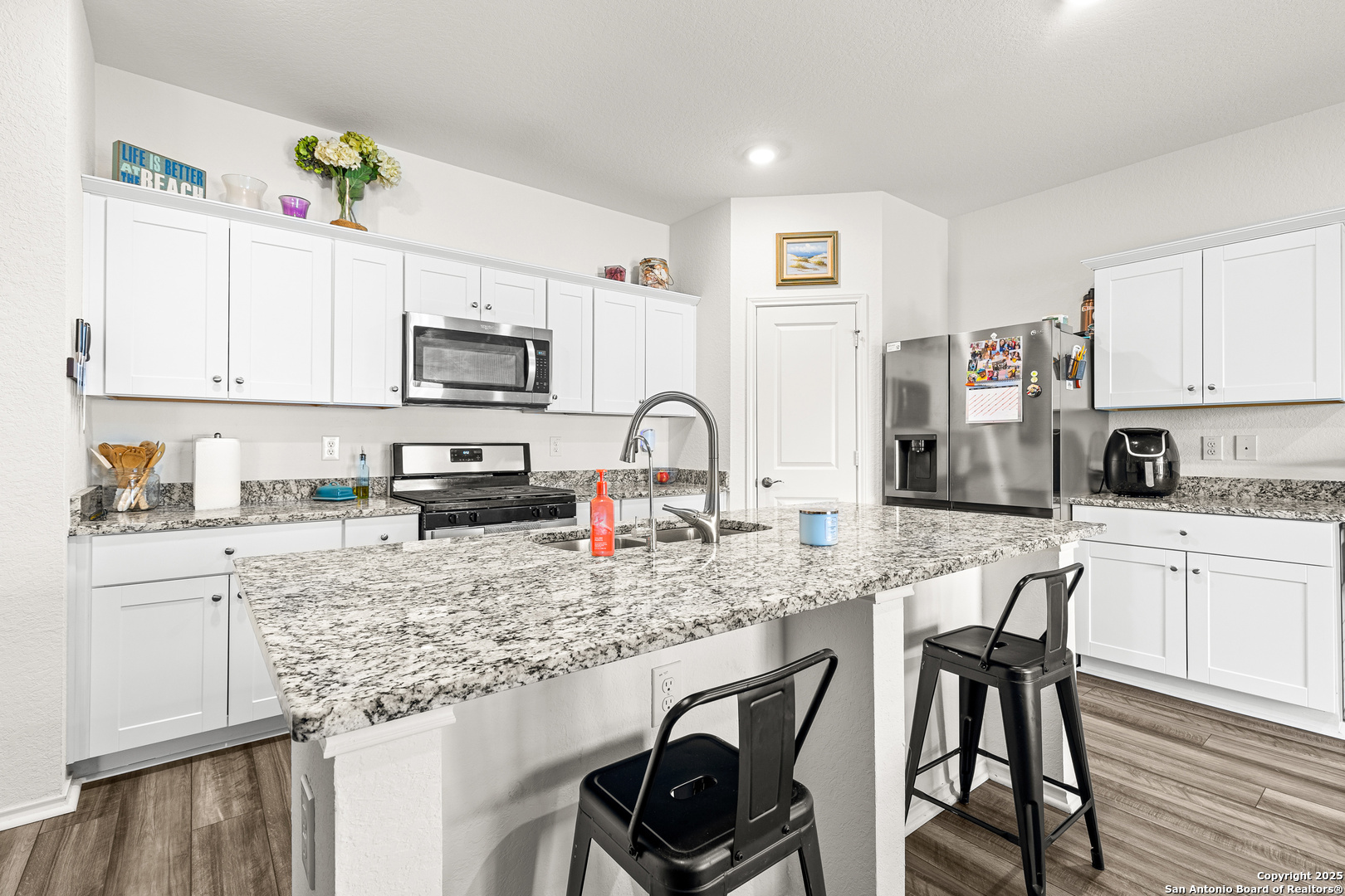 5259 Winding Streme St. Hedwig, TX 78152 - Photo 4 of 24 a kitchen with stainless steel appliances granite countertop a stove top oven a sink a dining table and chairs with wooden floor