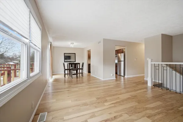 a view of an empty room with window and wooden floor