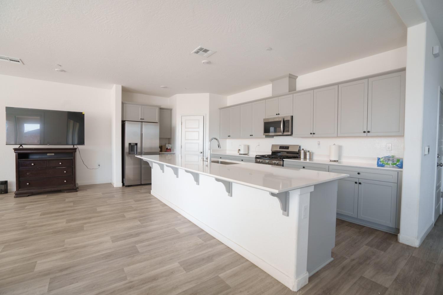 5769 West Austin Way Fresno, CA 93722 - Photo 10 of 32 a kitchen with stainless steel appliances a sink a stove a refrigerator cabinets and a center island