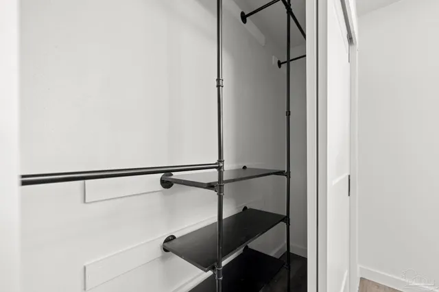a view of a hallway with wooden floor and closet area